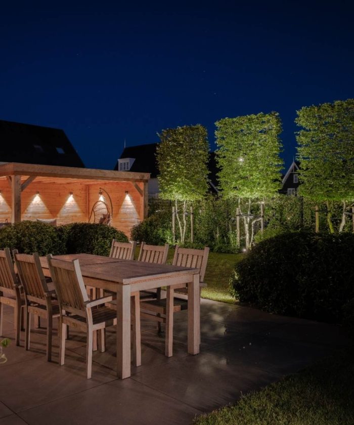 Luxe verlichte achtertuin met terras, tuin en overkapping